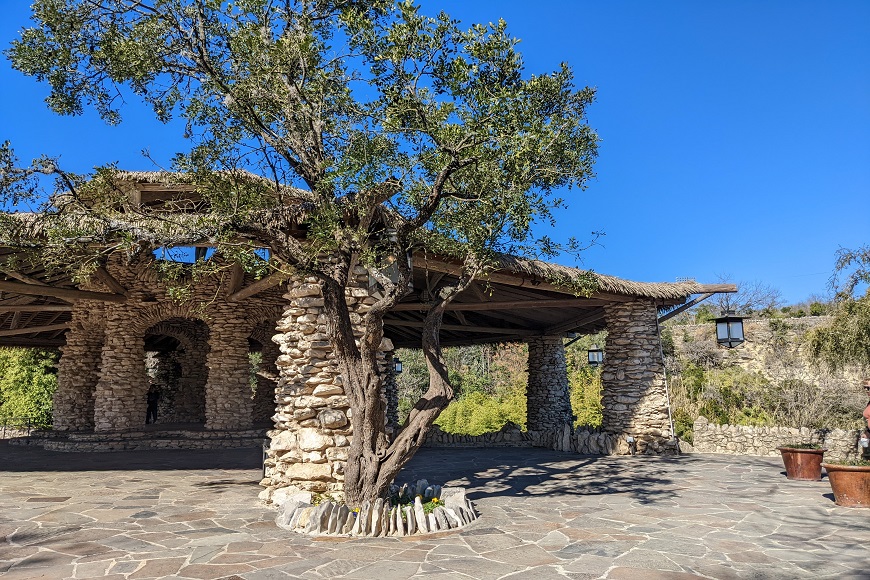 A stone gazebo with a tree in the middle.