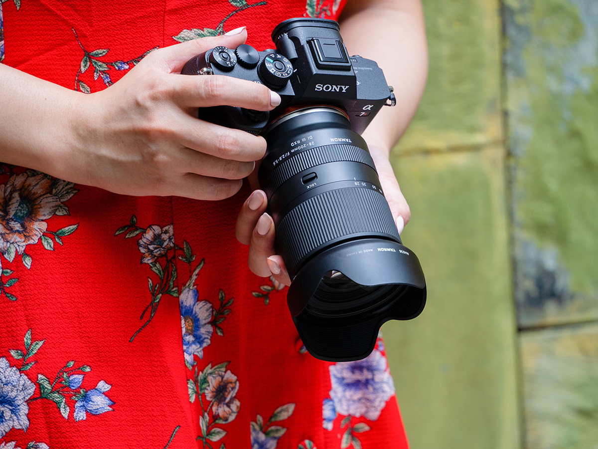 A woman in a red dress holding a camera.