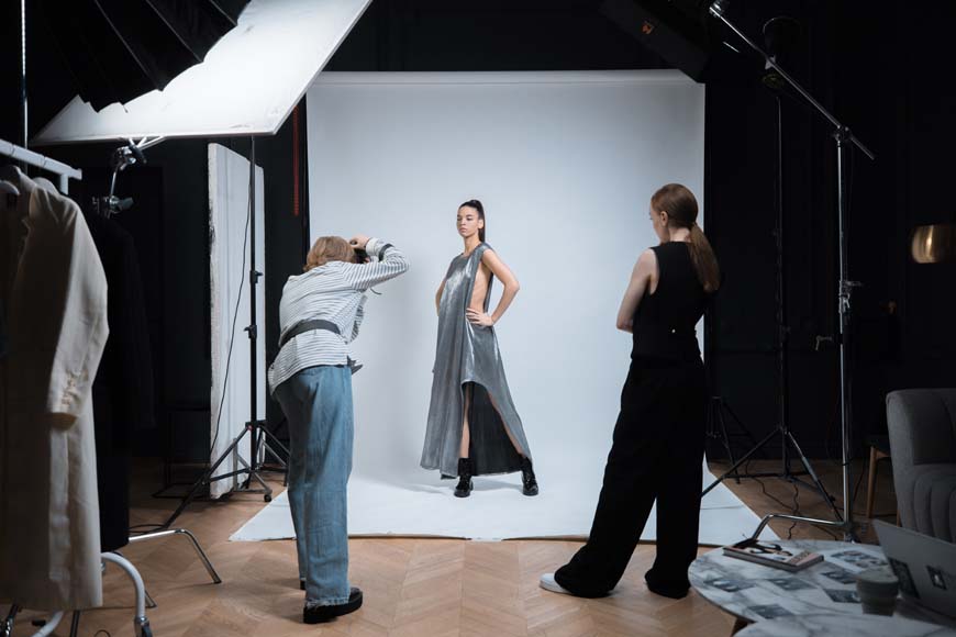 A woman is taking pictures of a model in a studio.