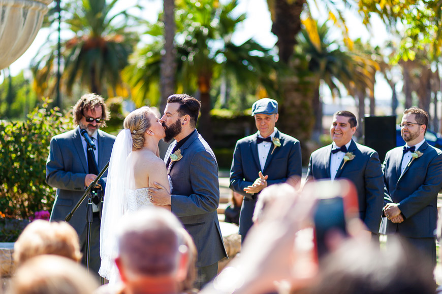A bride and groom kissing in front of a crowd of people.