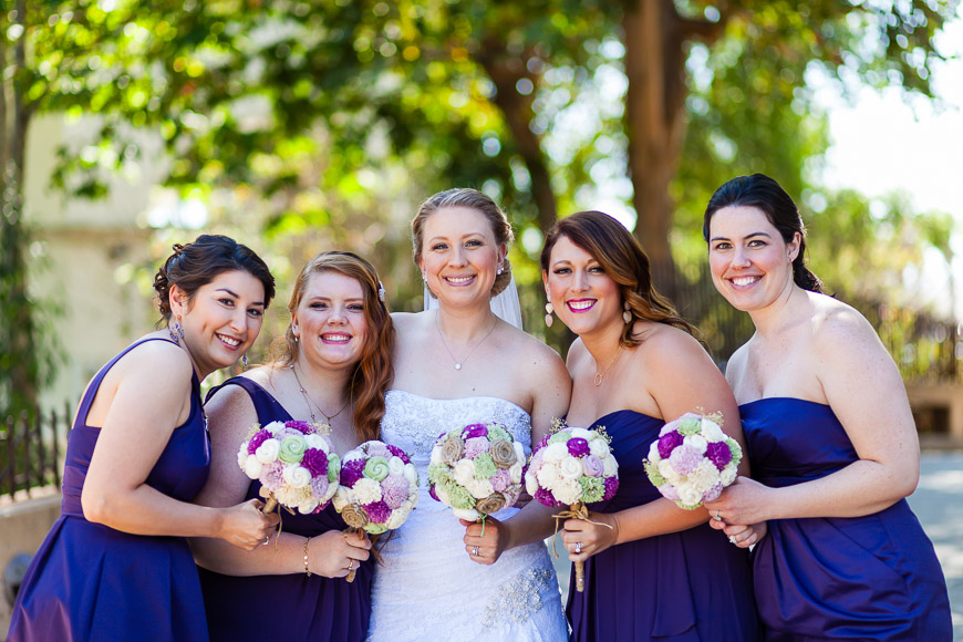 A group of bridesmaids in purple dresses pose for a picture.