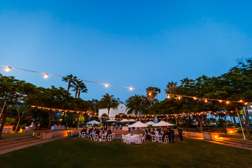 A wedding reception at dusk in front of palm trees.