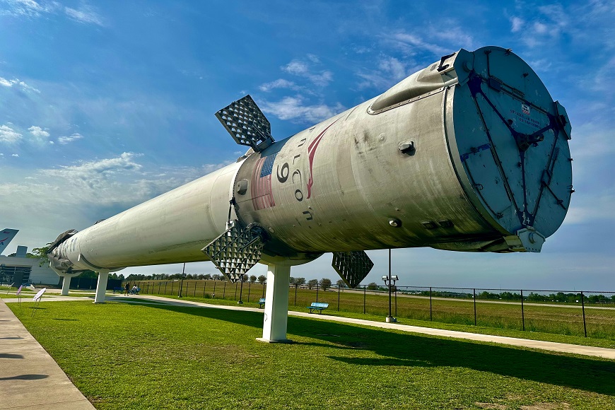 A large rocket on display in front of a grassy field.