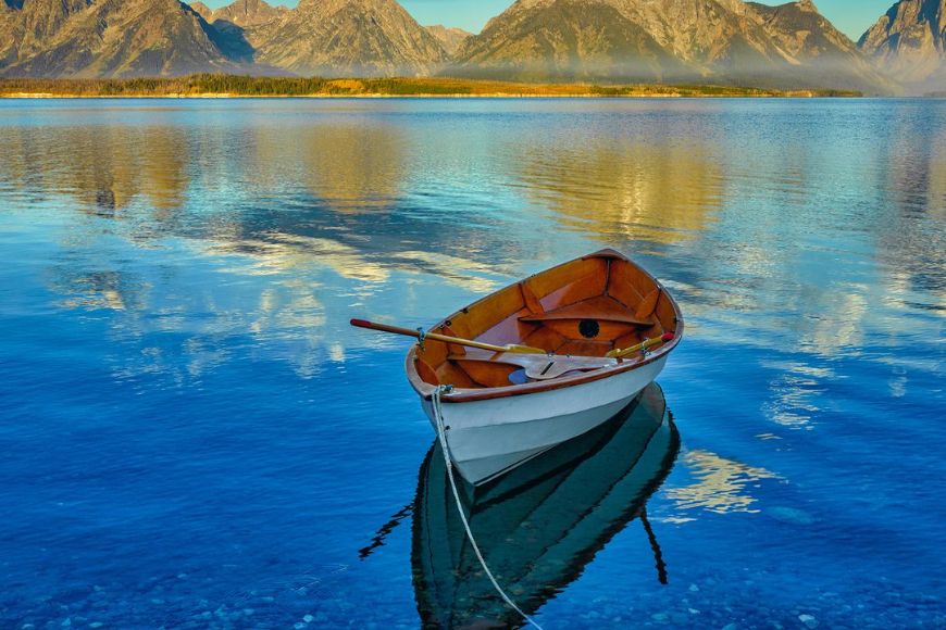 A boat sits on the water with mountains in the background.