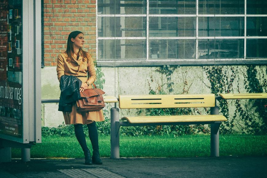 A woman is standing next to a bus stop.