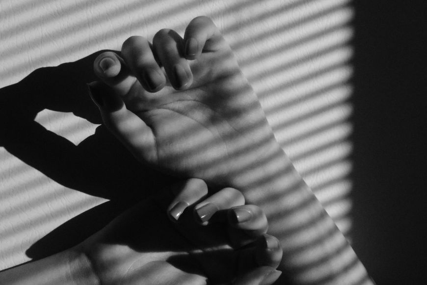 A black and white photo of a woman's hand against a window.
