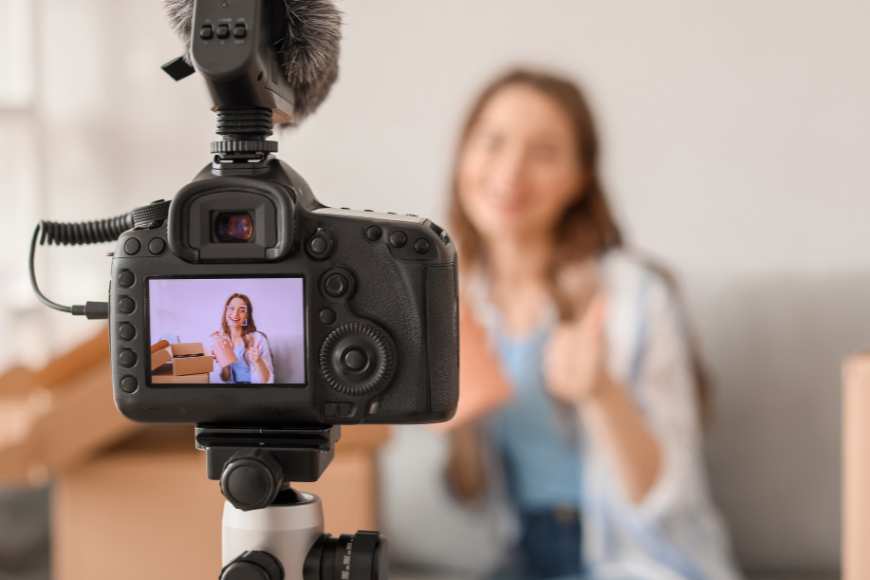 A woman with a camera, filming a video.