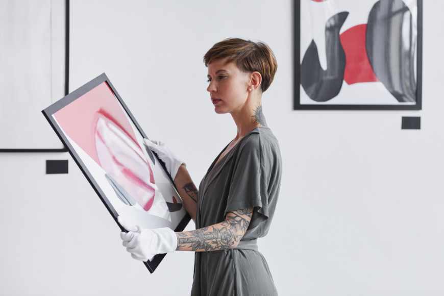 Artist holding a painting while planning an art gallery.