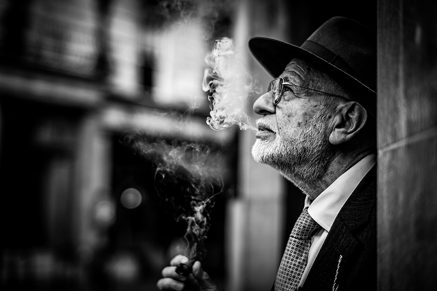A man in a hat smokes a cigarette.