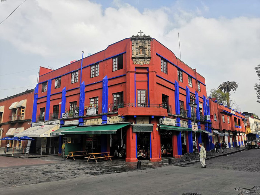 A red and blue building on a street corner.