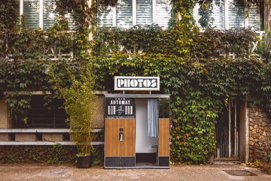 A photo booth in front of a building with ivy growing on it.