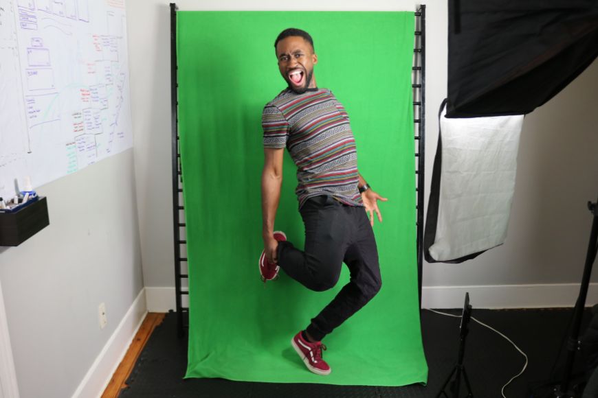 A man posing in front of a green screen.