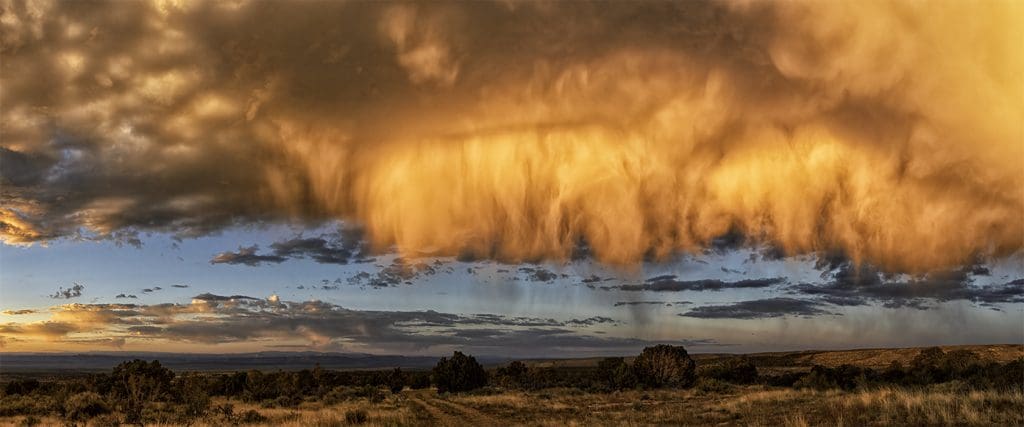A storm cloud over a field at sunset.