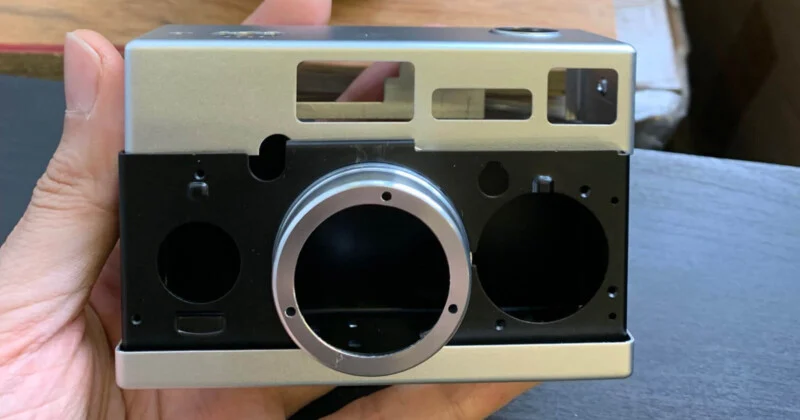 A person holding a silver camera with a hole in it.