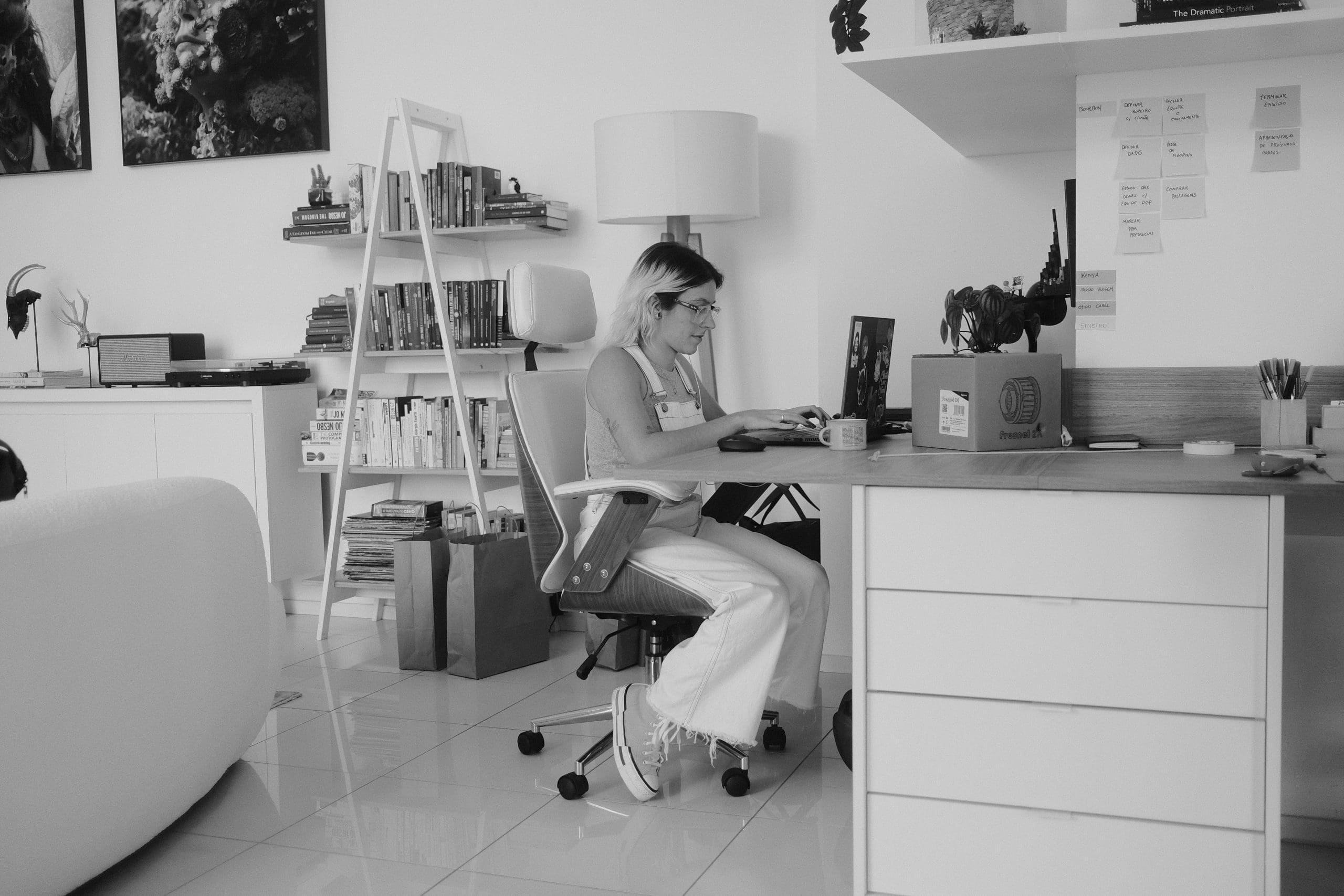 A black and white photo of a woman working at a desk.