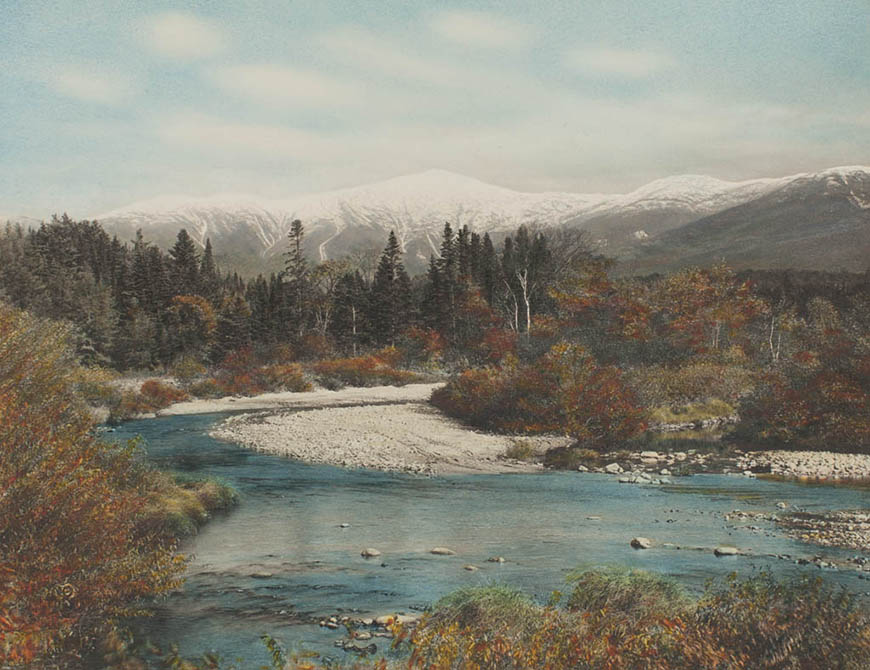 A photo of a river with mountains in the background.