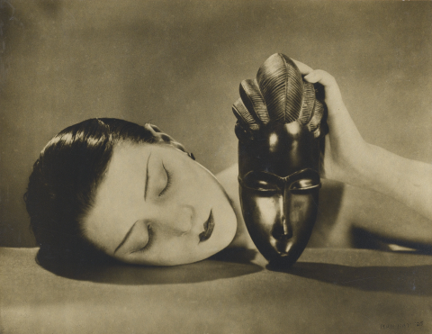 A black and white photo of a woman laying on top of a mask.