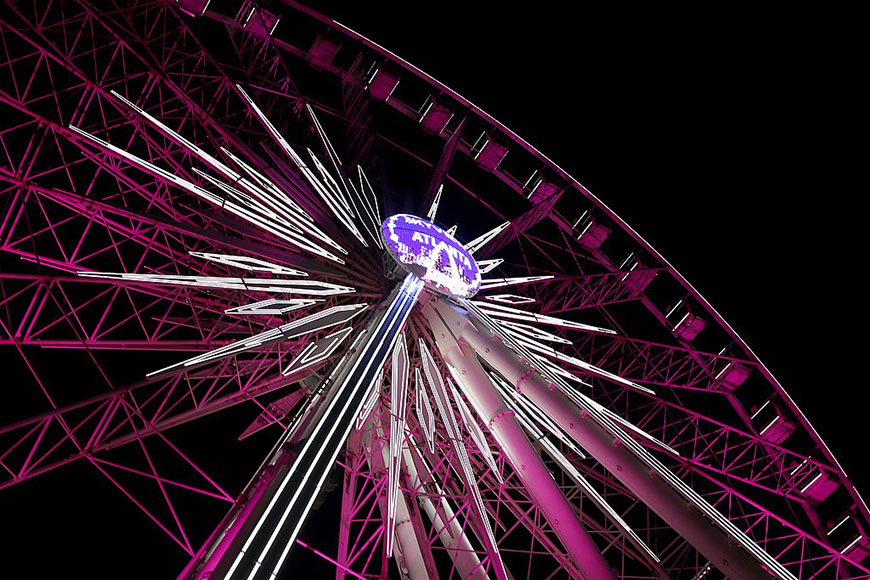 A ferris wheel is lit up at night.