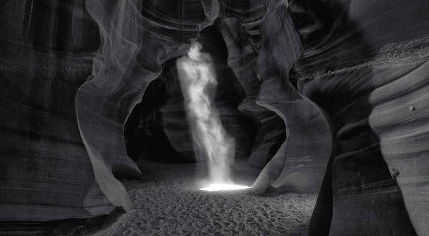 A black and white photo of a waterfall in a canyon.