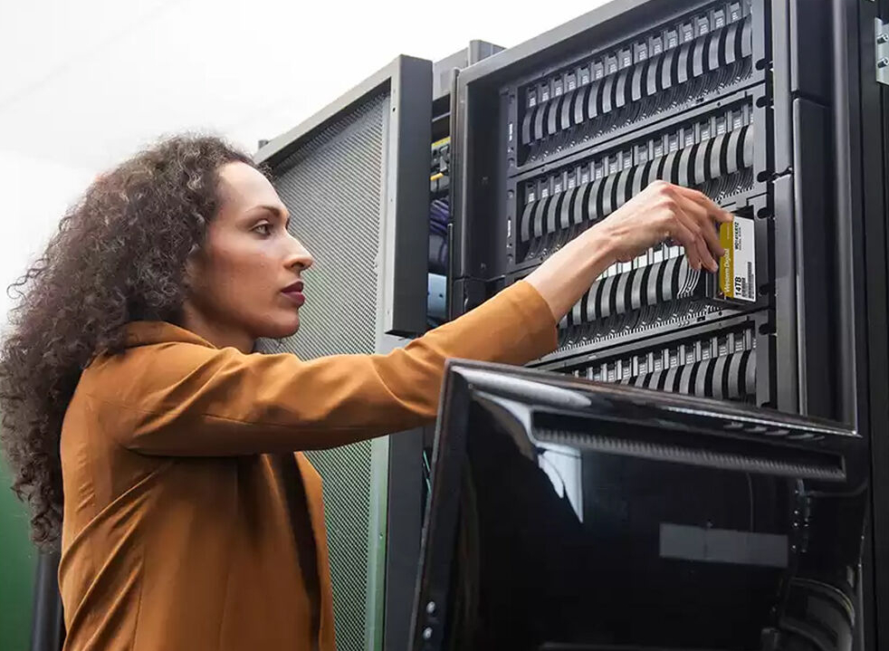 A woman is putting an HDD into a server rack.