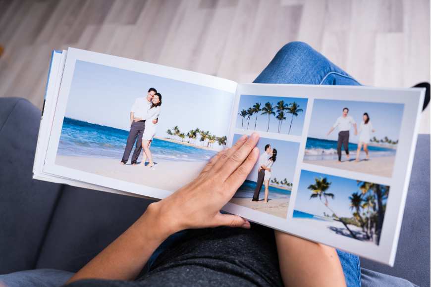 A woman is sitting on a couch and holding a photo album.