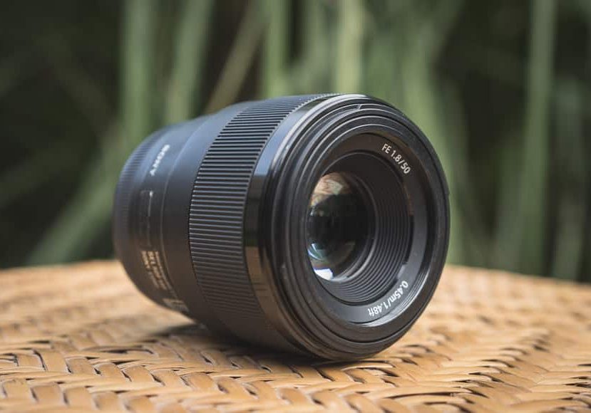 A black lens sitting on a wicker chair.