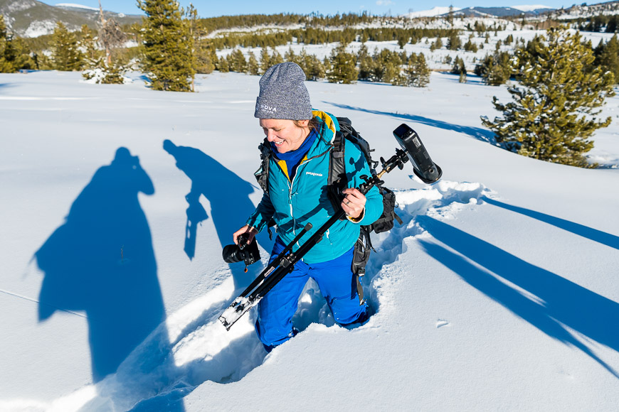 A woman walking through the snow with her skis.
