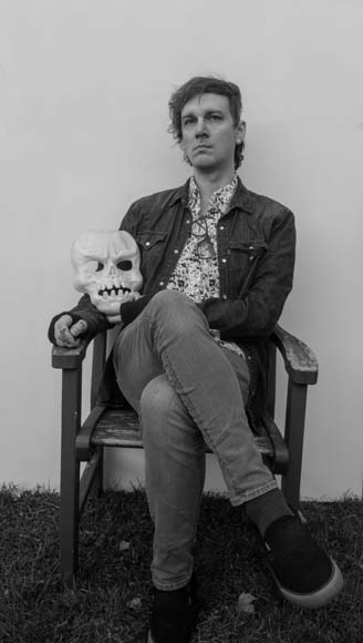 A man sitting in a chair holding a skull.