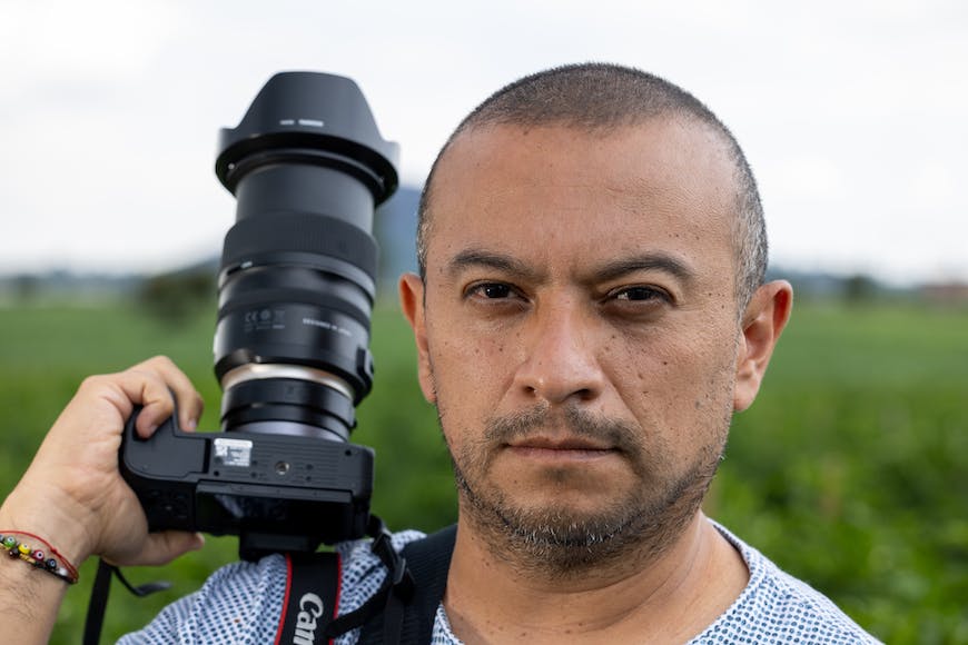 A man holding a camera in front of a field.