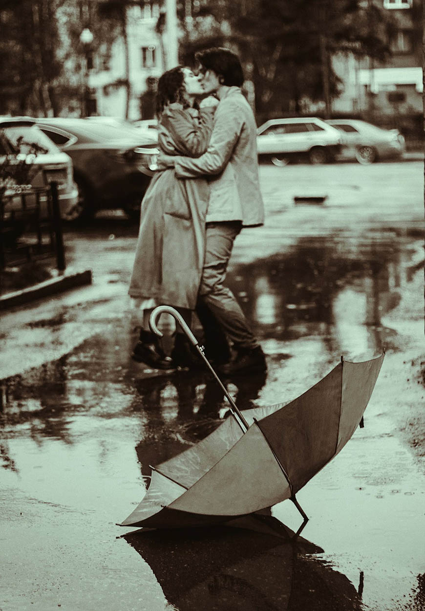 A man and a woman kissing in the rain.