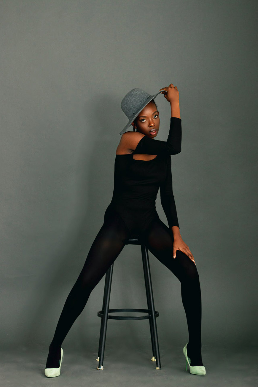 A black woman posing on a stool.