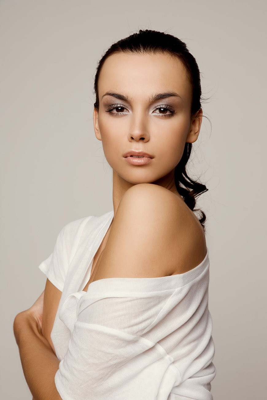 A beautiful woman in a white shirt posing with her arms crossed.