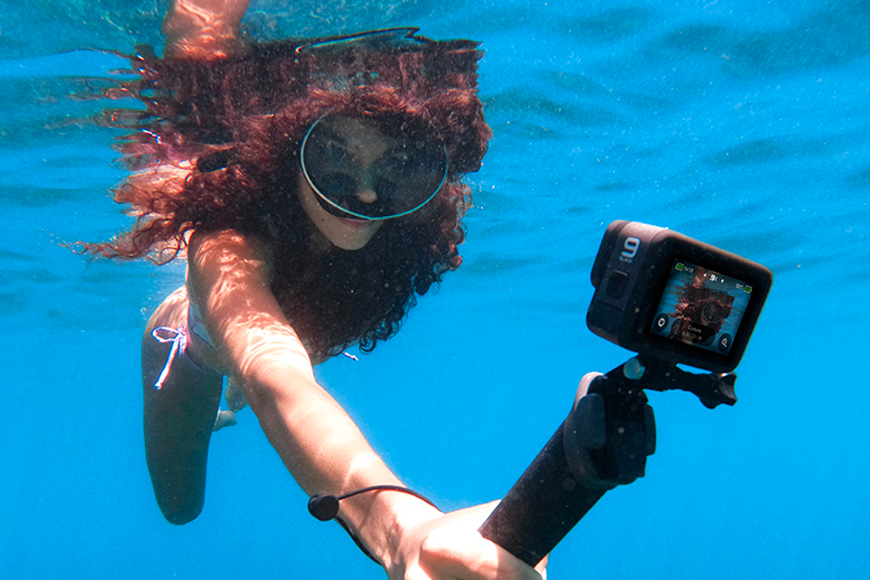 A woman holding a gopro underwater.