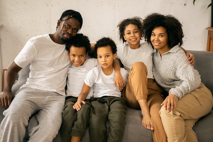 A black family sitting on a gray couch.