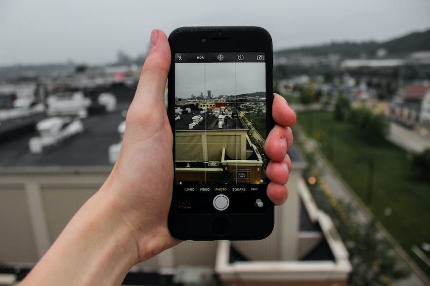 A person holding up a cell phone with a view of a city.