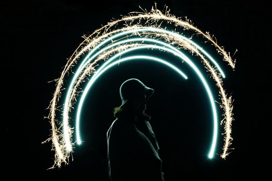 A person in a hat with sparklers in his hands.