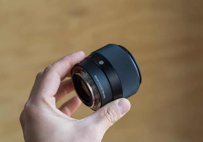 A person holding a small lens on a wooden table.