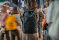A woman with a backpack on a busy street.