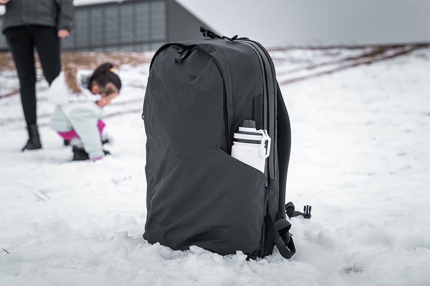 A black backpack with a child in the snow.