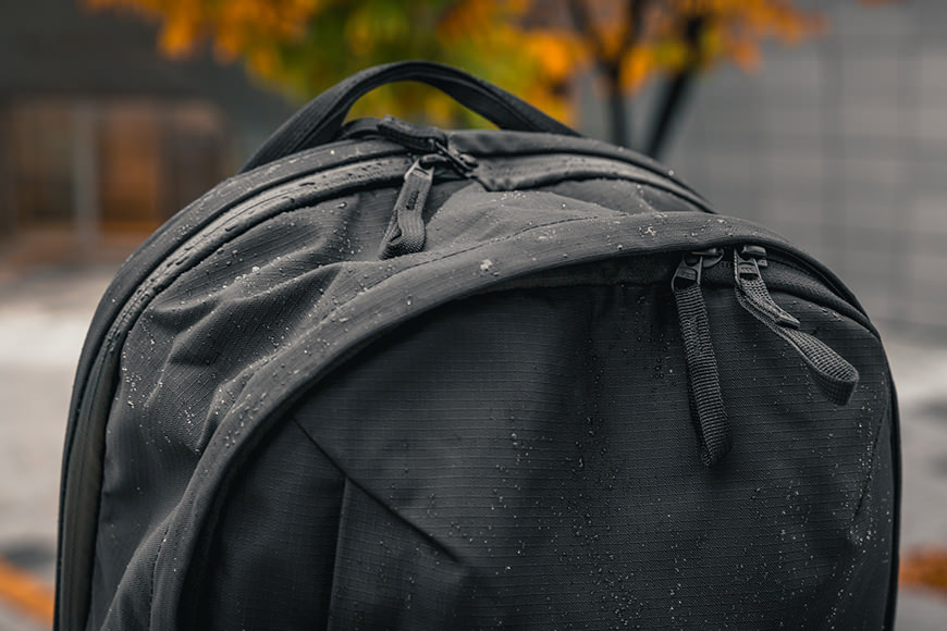 A black backpack sitting on a sidewalk.