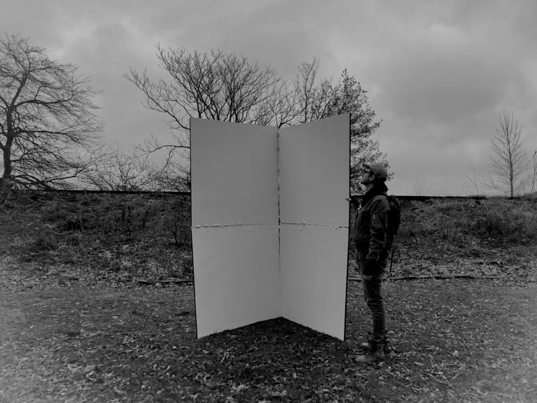 A man standing in front of a large white sheet of paper.