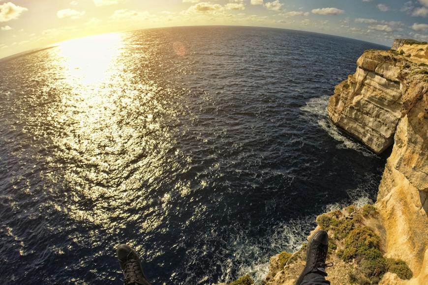 A person is standing on a cliff overlooking the ocean.