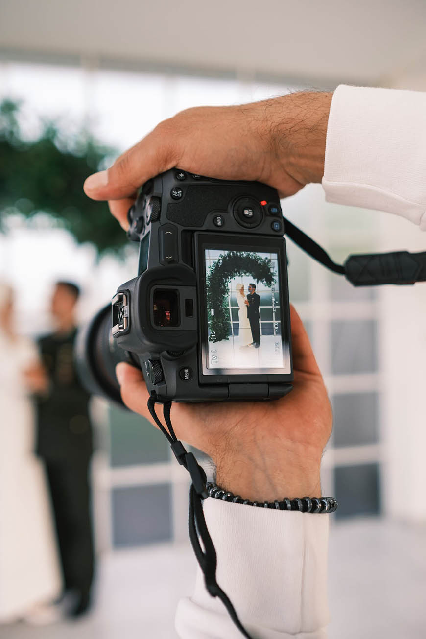 A man is holding a camera and taking a picture of a bride and groom.