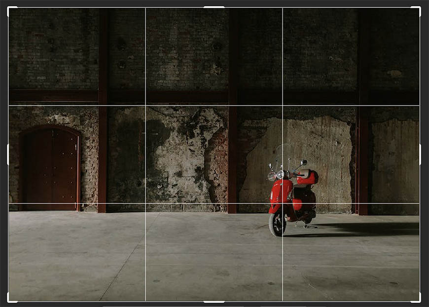A red scooter is parked in an empty room.