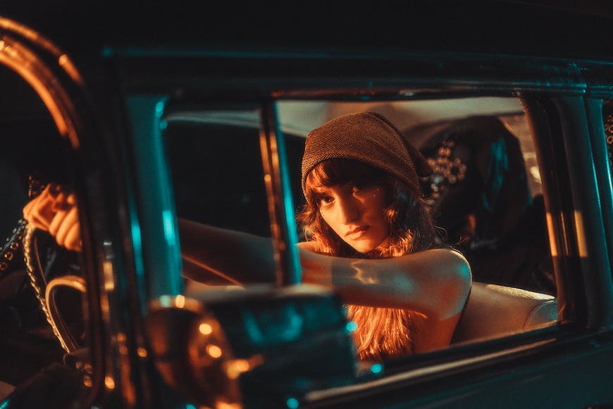 A woman sitting in the driver's seat of an old car.