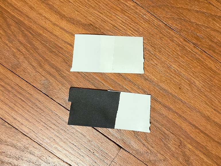 Two pieces of black and white tape on a wooden floor.