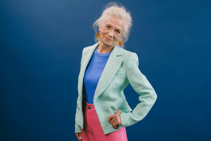 An older woman in a blue blazer and pink skirt.