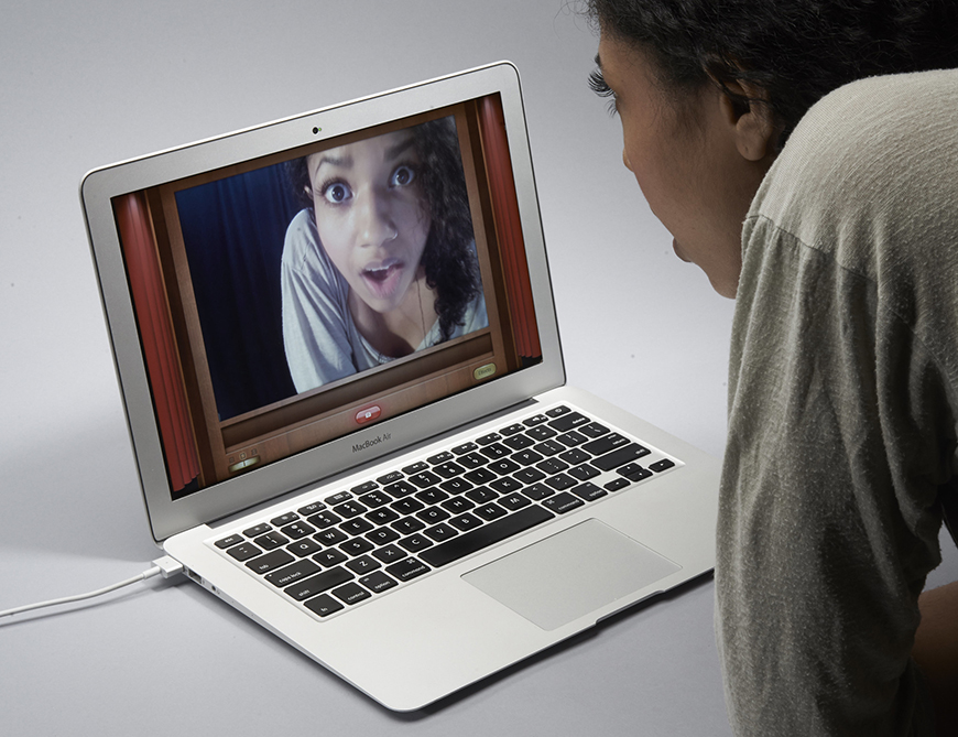 A woman is looking at a screen on a laptop.