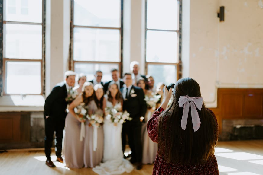 A bride and groom taking a picture of their wedding party.