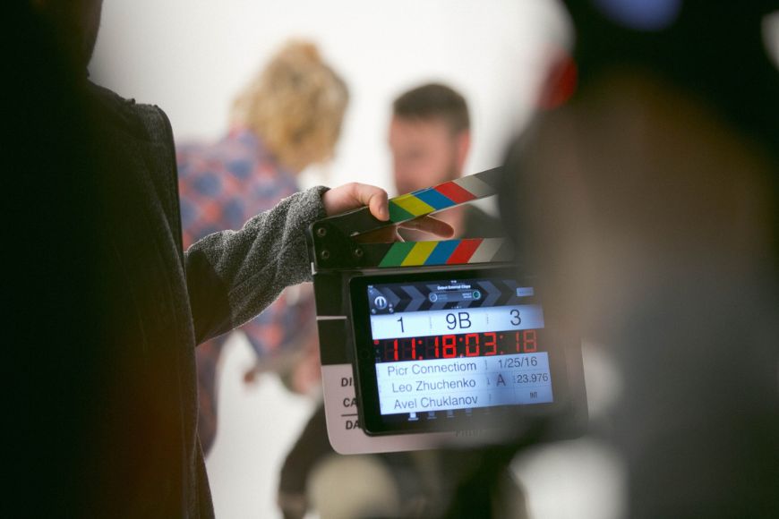 A person holding a clapper board in front of a camera.